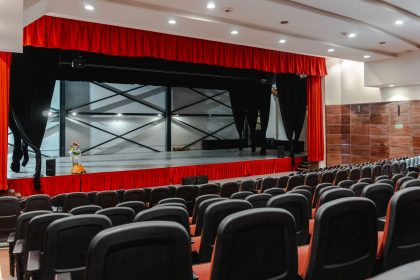 Teatro vazio com cortinas vermelhas abertas e palco iluminado, pronto para uma apresentação